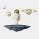 The White & Gold Orbit Odyssey Astronaut 3D Wall Art by Giant Sculptures captures the charm of a small astronaut with a gold visor on a floating rock, surrounded by three black and white spheres, including one with gold rings reminiscent of a planet.