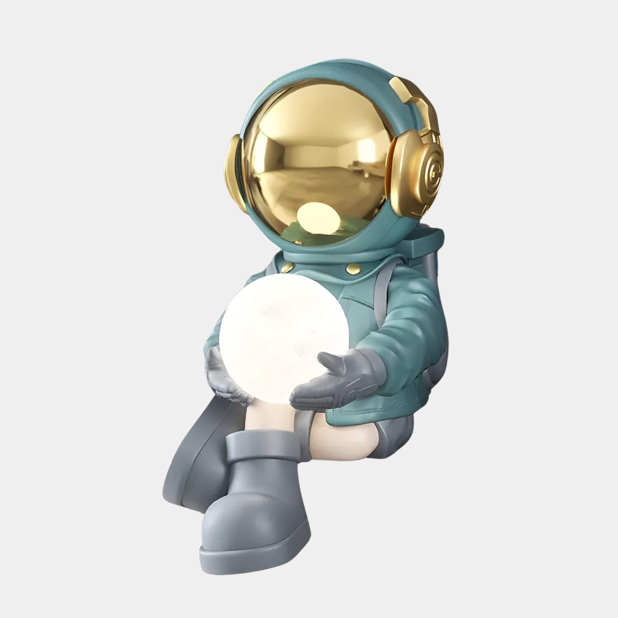 The 53cm Galactic Blue Astronaut Glow Seated I Sculpture by Giant Sculptures features a small figurine with a reflective gold helmet, dressed in teal and gray attire, seated and holding a softly glowing white orb against the light gray background.