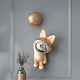 The Giant Sculptures Rose Gold Astronaut Bunny Balloon 3D Wall Art (70cm) is displayed above a modern vase on a gray wall, its gold moon-shaped balloon adding cosmic flair to this minimalist, contemporary space.