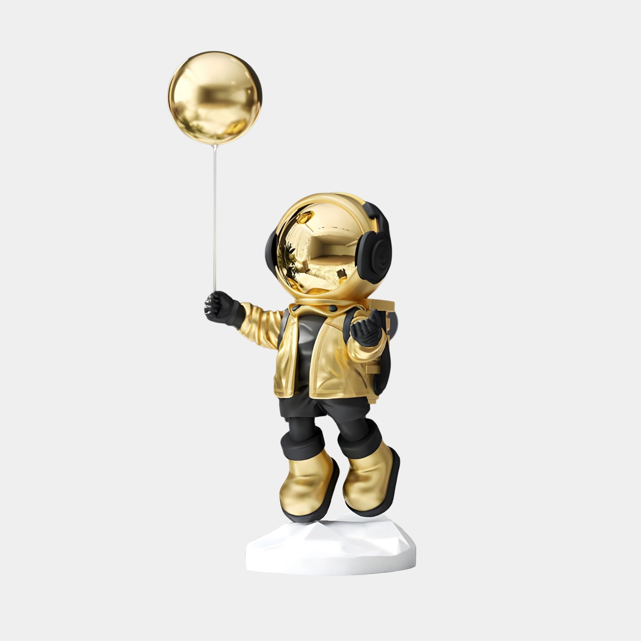 The Celestial Gold Astronaut Balloon Sculpture by Giant Sculptures, standing 55cm tall, features a shiny suit with black-accented gloves and boots while holding a metallic gold balloon. It stands on a white base against a plain backdrop, bringing an out-of-this-world charm to any space.