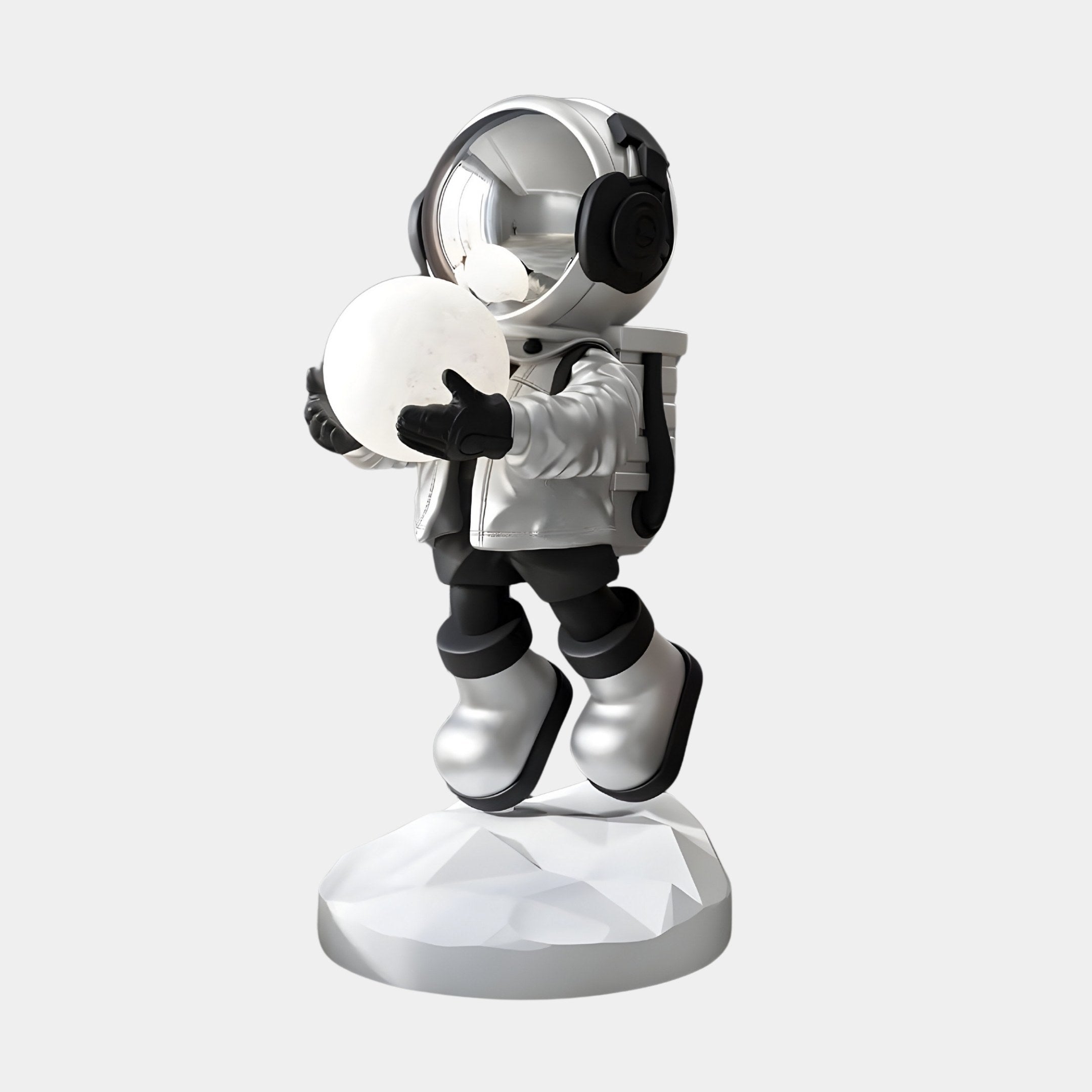 The Lunar Silver Astronaut Glow Hover Sculpture by Giant Sculptures features a sleek black-suited figure holding a glowing white sphere as a touch switch. It stands on a textured circular base, embodying the appearance of floating effortlessly like a lamp in neutral space.