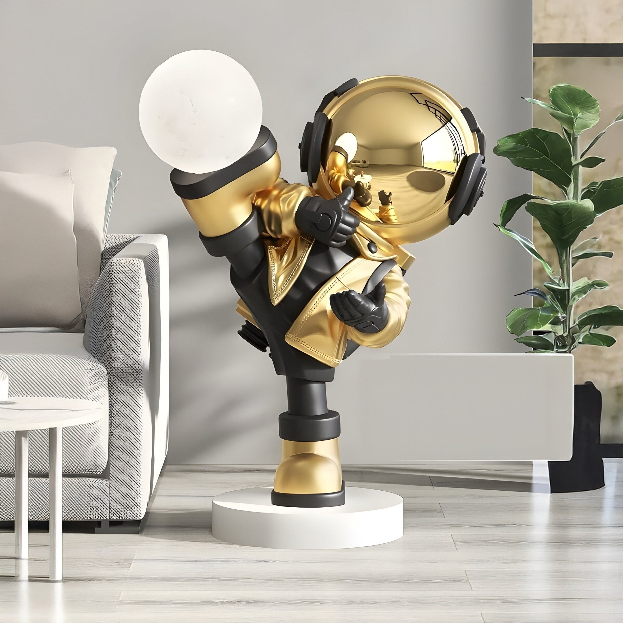 The Celestial Gold Astronaut Glow Kick Sculpture from Giant Sculptures showcases a glossy gold astronaut in a dynamic pose on a white circular base, holding a sphere and wearing headphones. It features adjustable lighting and complements modern living spaces with its artistic design and subtle illumination.