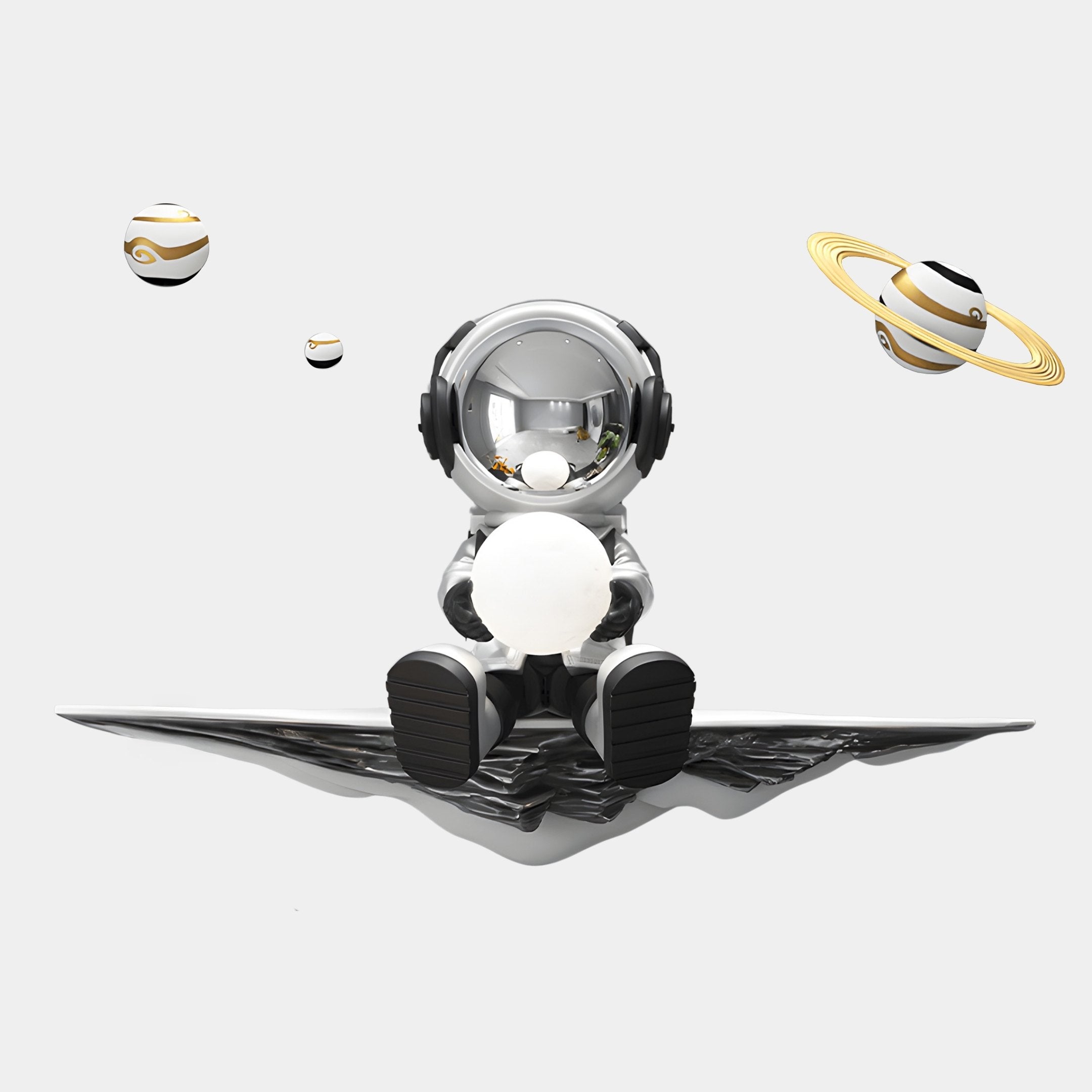 A small astronaut figurine from Giant Sculptures Silver 3D Dreamer Glow Astronaut Wall Art sits on a metallic surface, holding a sphere. Futuristic abstract planetary shapes, including one with Saturn-like rings, surround it on a plain white background that enhances the ambient effect.