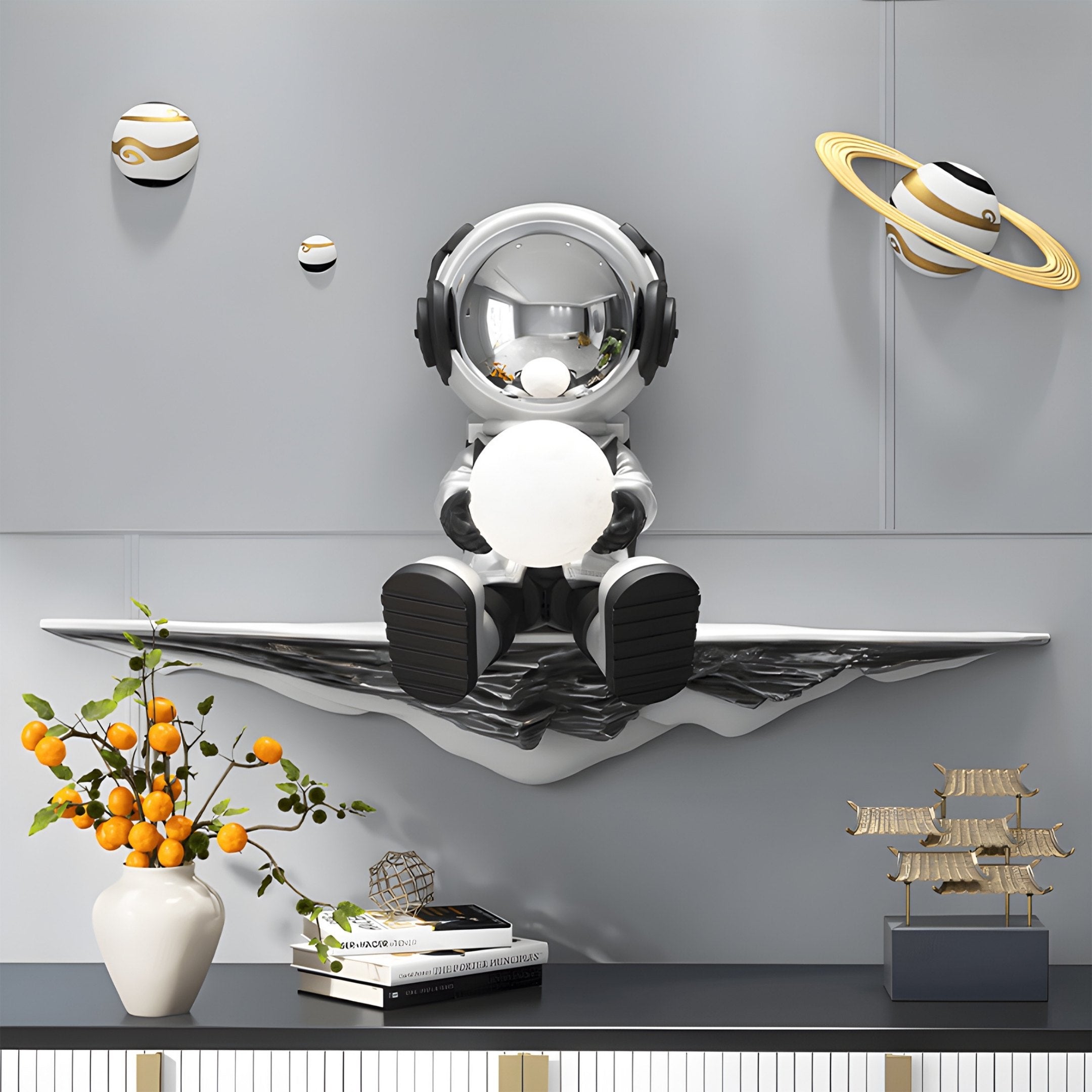 A futuristic room showcases Giant Sculptures Silver 3D Dreamer Glow Astronaut Wall Art, featuring a glowing orb on a wave-like platform with floating planetary models for an ambient effect. A white vase with orange flowers enhances the scene alongside a small pagoda structure.