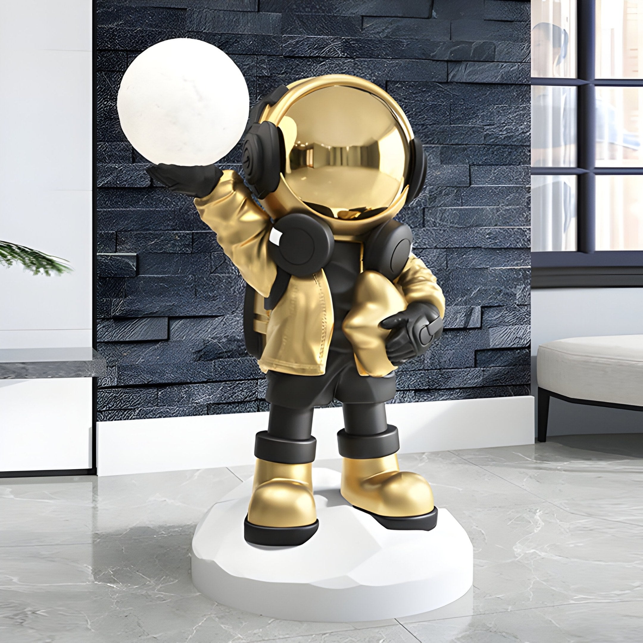 The Celestial Gold Astronaut Beats Glow Orb Sculpture by Giant Sculptures, standing 75cm tall, features an astronaut holding a glowing sphere. It contrasts against a dark textured wall and light floor.