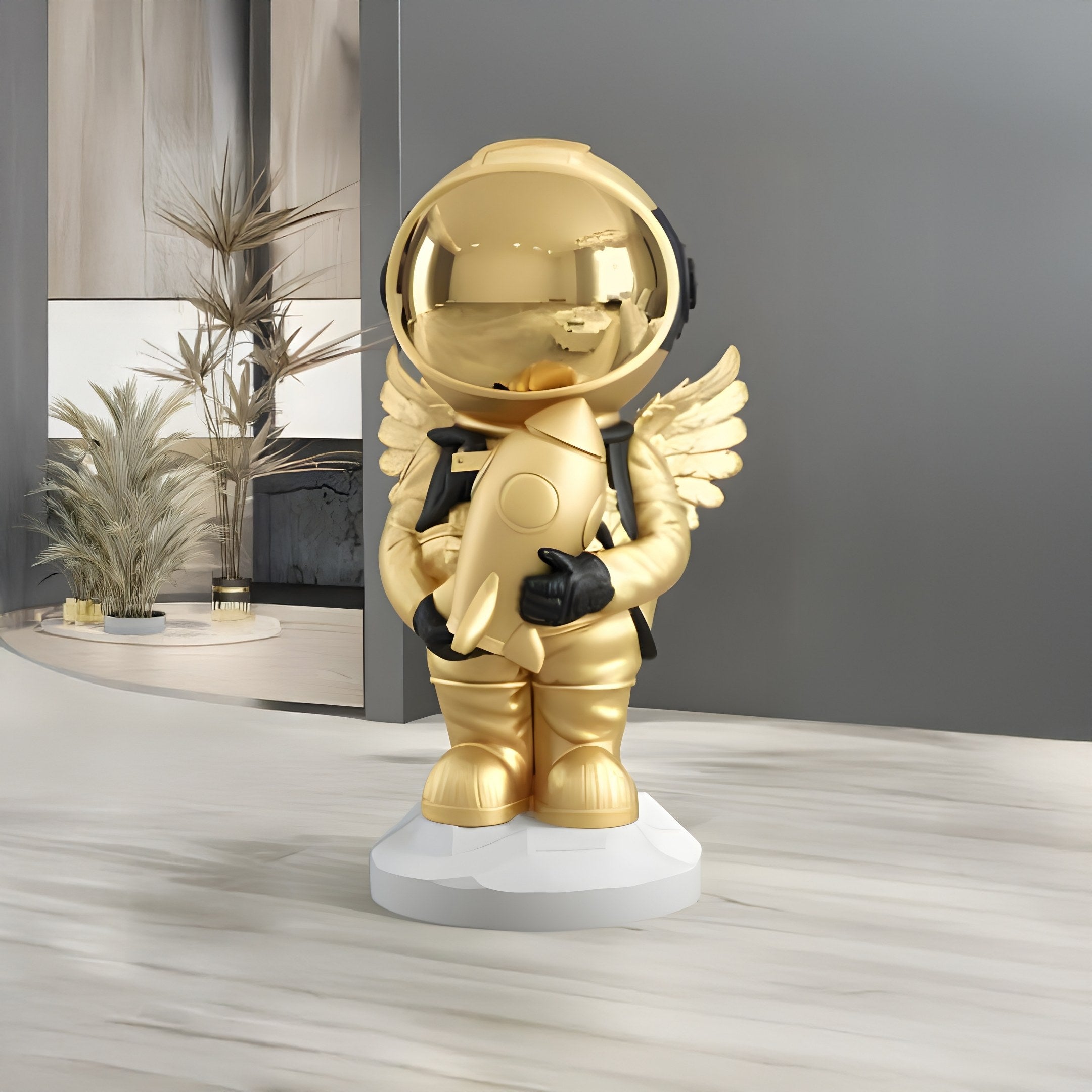 The Celestial Gold Astronaut Angel Rocket Sculpture by Giant Sculptures stands on a pedestal in a modern indoor space, with angelic wings and holding a rocket. Its surrounded by celestial decor featuring minimalist accents, plants, and neutral-colored walls.