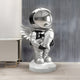 The Lunar Silver Astronaut Angel Rocket Sculpture by Giant Sculptures stands majestically on a display pedestal. Its reflective helmet contrasts with the modern gray wall, while a white desk peeks from the left, creating a cosmic highlight in any room.