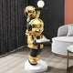 The Celestial Gold Astronaut Duo Server Sculpture (78cm) by Giant Sculptures features stacked gold astronauts—one holding a glowing orb, the other serving with a tray and book—creating a bold, functional accent in any modern space.