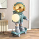 The Giant Sculptures Galactic Blue Skater Astronaut Glow Sculpture - 80cm features a gold-helmeted astronaut with headphones on a skateboard, holding a glowing sphere—perfect for adding modern decorative lighting to contemporary spaces.