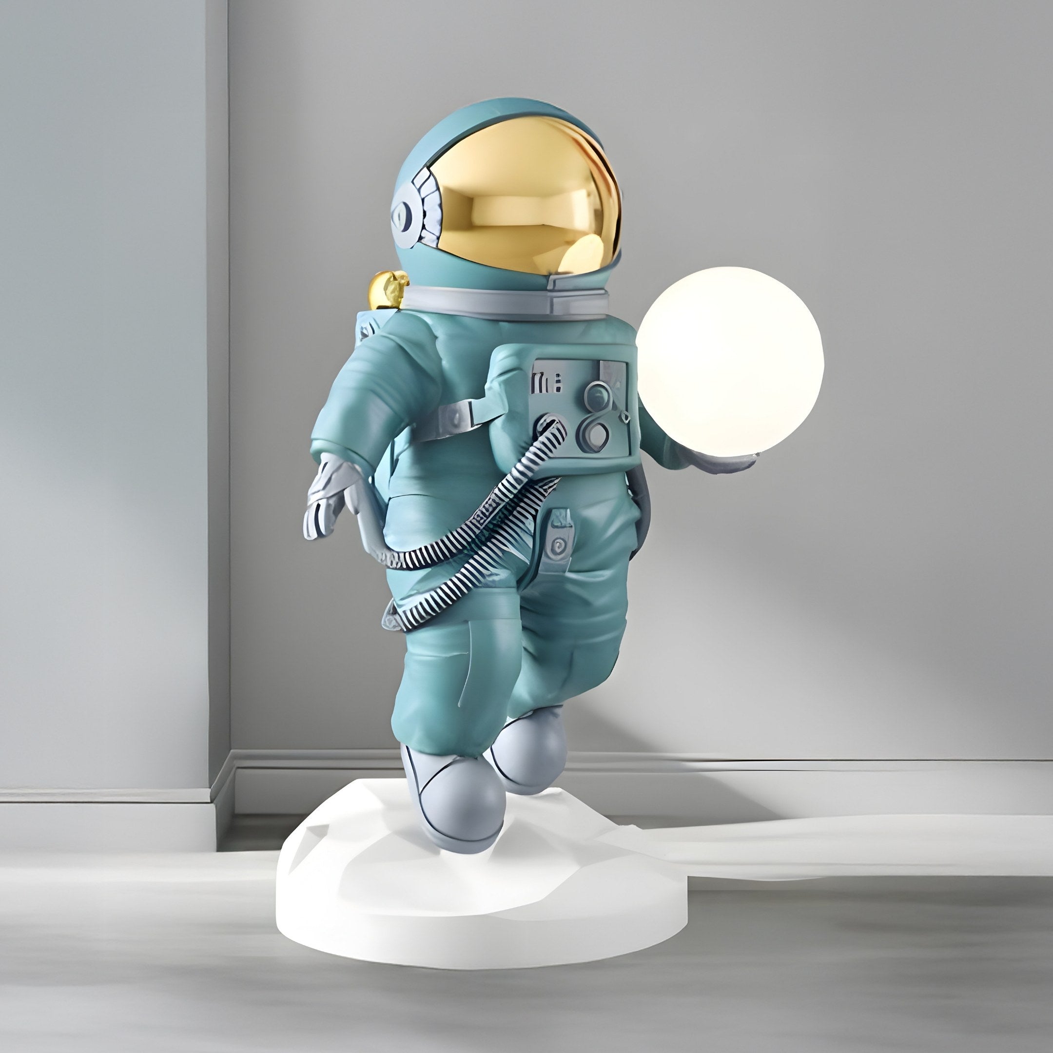 The Giant Sculptures Galactic Blue Astronaut Ranger Glow Orb Sculpture - 80cm features a galactic blue astronaut with a reflective gold visor on a white base, holding a glowing orb. The minimalist setting enhances its futuristic décor appeal.