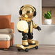 The Celestial Gold Skater Astronaut Glow Sculpture - 80cm by Giant Sculptures stands on a skateboard with a glowing orb, styled indoors near a beige sofa and green plant for striking modern decor.