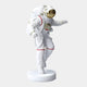 The Giant Sculptures 85cm White Space Astronaut Explorer Sculpture showcases a resin astronaut with a gold-tinted visor and backpack on a round base. Its right arm is raised, left by its side, against a gray backdrop, making a cosmic statement.