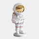 The Nova White Astronaut Star Sculpture by Giant Sculptures stands 85cm tall, featuring a star-holding astronaut in a white spacesuit with red accents on a circular base. Its shiny gold visor and large, reflective helmet make it an eye-catching piece of cosmic décor.