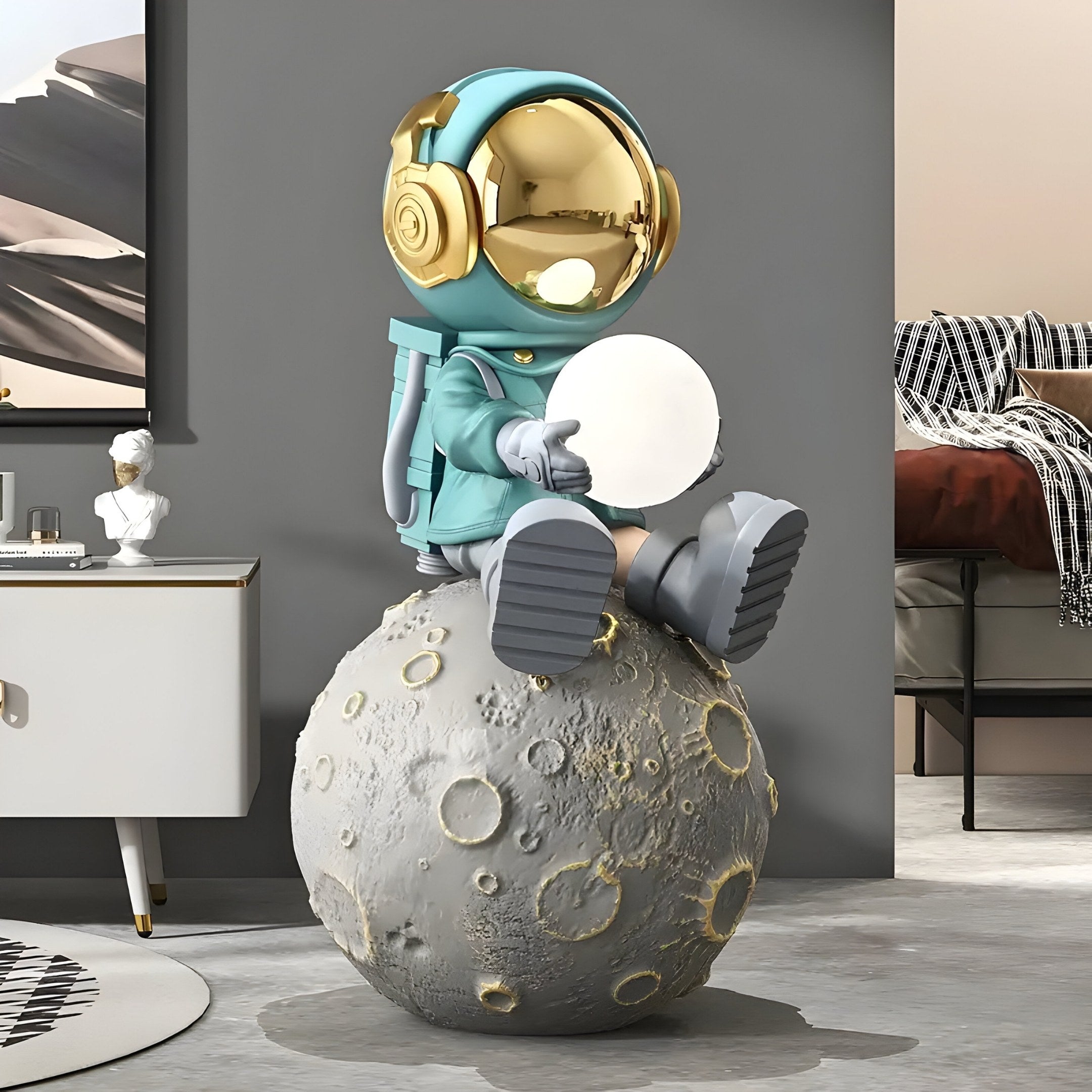 The 86cm Galactic Blue Astronaut Glow Moon Sculpture by Giant Sculptures features a whimsical astronaut in turquoise with a gold helmet, holding a round object. Its set in an eclectic modern room, adding a unique touch to the decor.