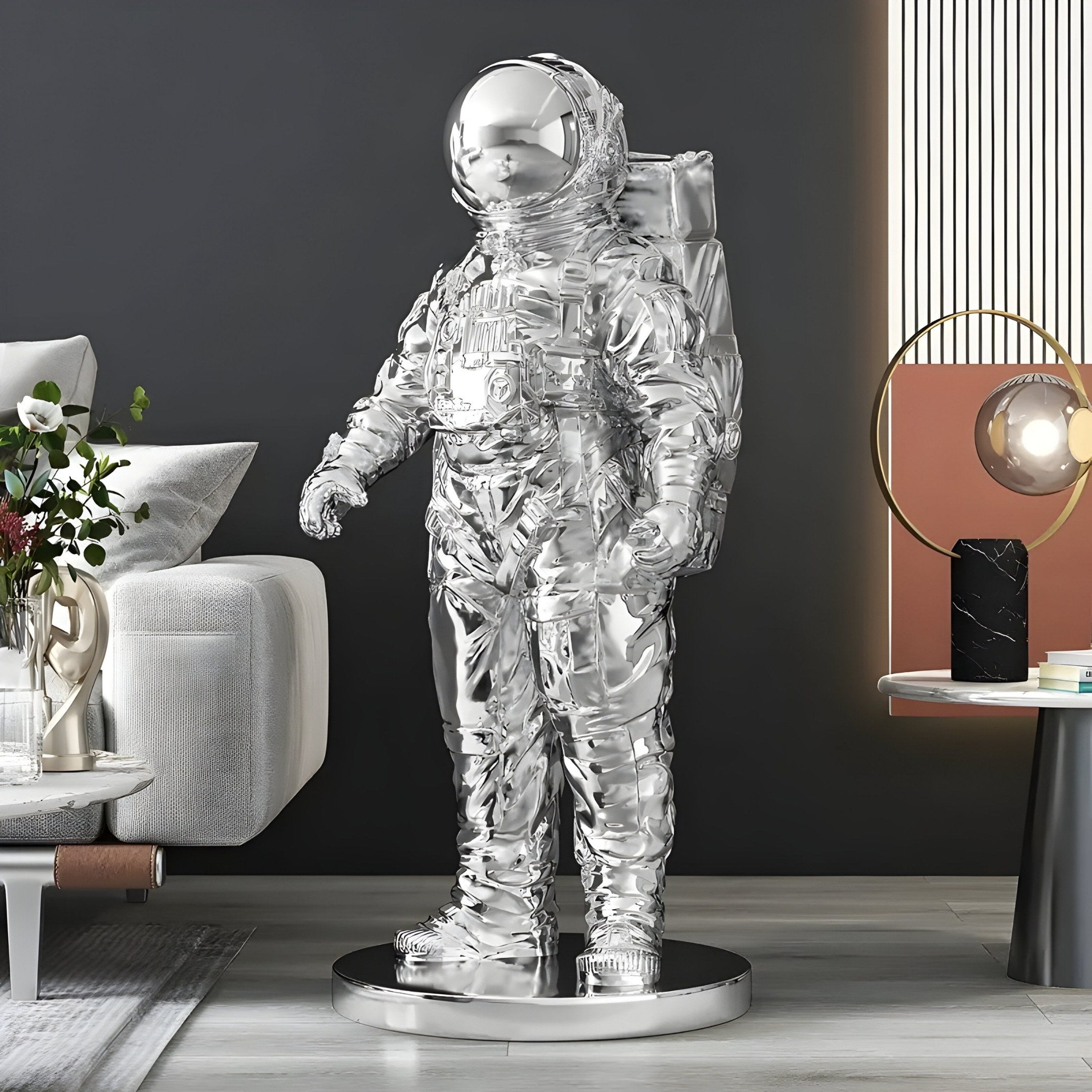 The Cosmic Chrome Space Astronaut Standing Sculpture by Giant Sculptures, with its shiny chrome finish, elevates a modern living rooms space-inspired décor. Placed near a sleek sofa and globe lamp, its futuristic presence is enhanced by dark walls that amplify the reflective surfaces.