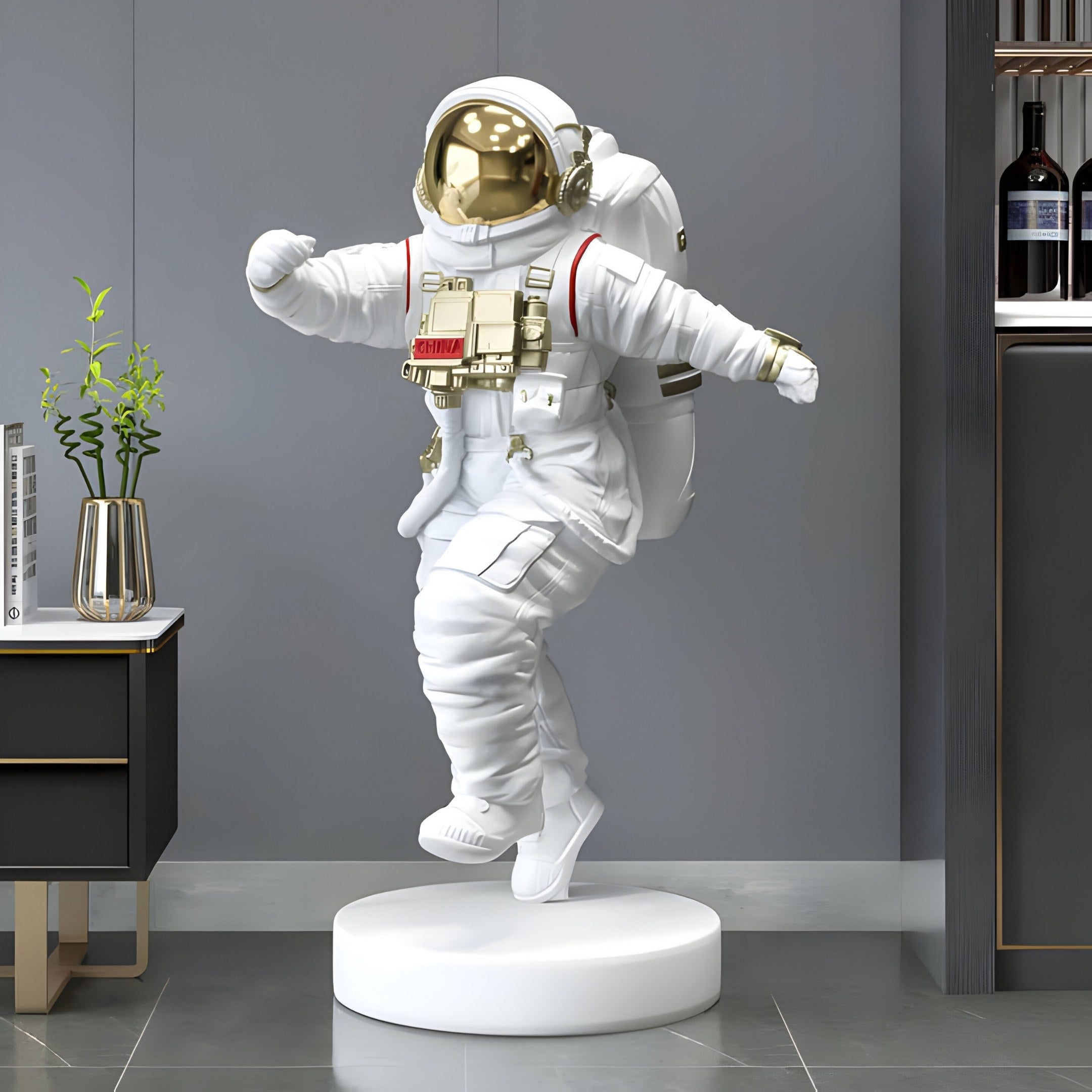 The White Space Astronaut Strider Sculpture - 90cm by Giant Sculptures features a playful astronaut in a white spacesuit with a gold visor, posed as though dancing on one foot. Ideal for space-inspired decor, its perfect for indoor display next to plants and cabinets.