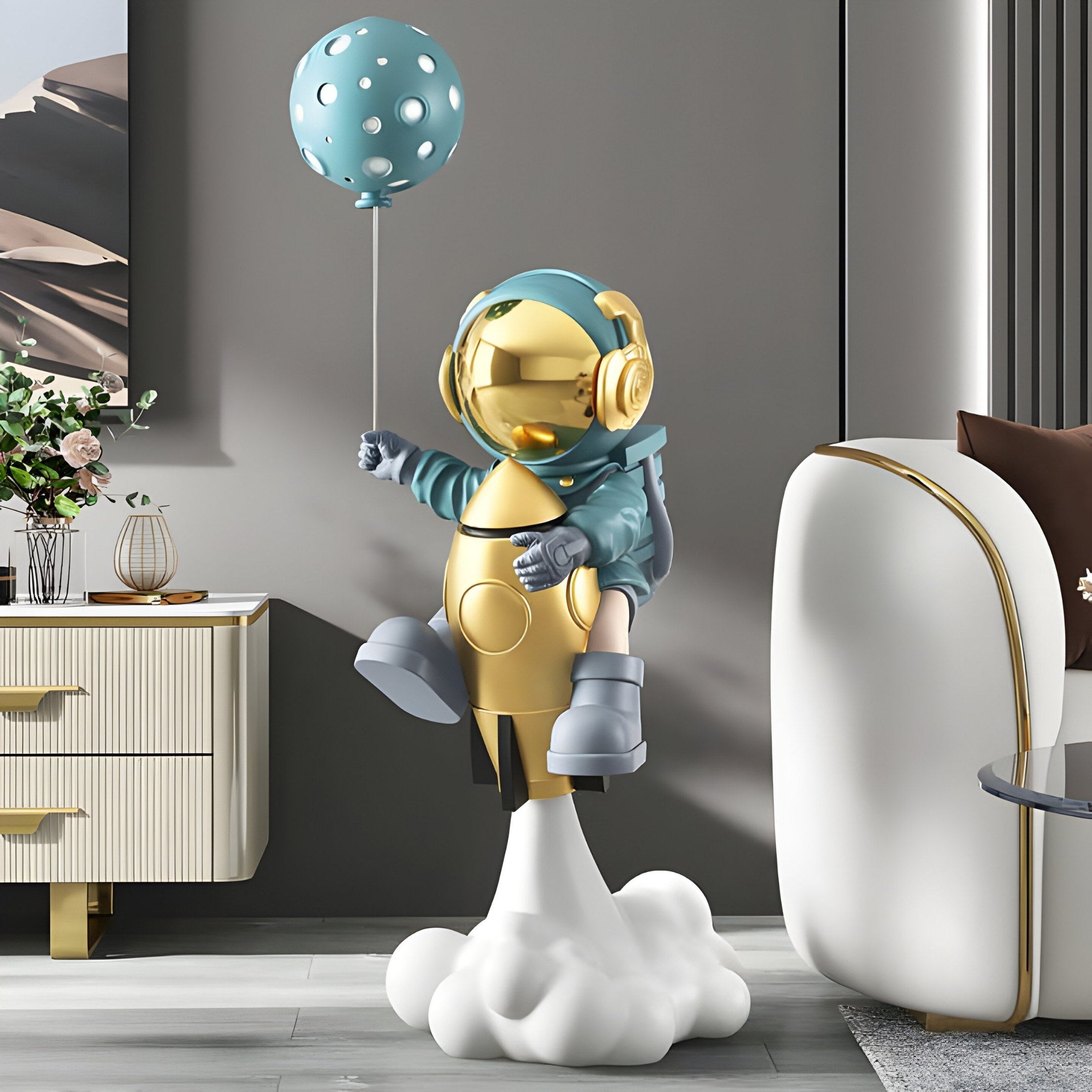 The Galactic Blue Astronaut Rocket Lift-Off Balloon Sculpture (95cm) by Giant Sculptures features an astronaut in a space helmet on a golden rocket with a dotted balloon, complementing a stylish room with a beige chair and flower-adorned cabinet.