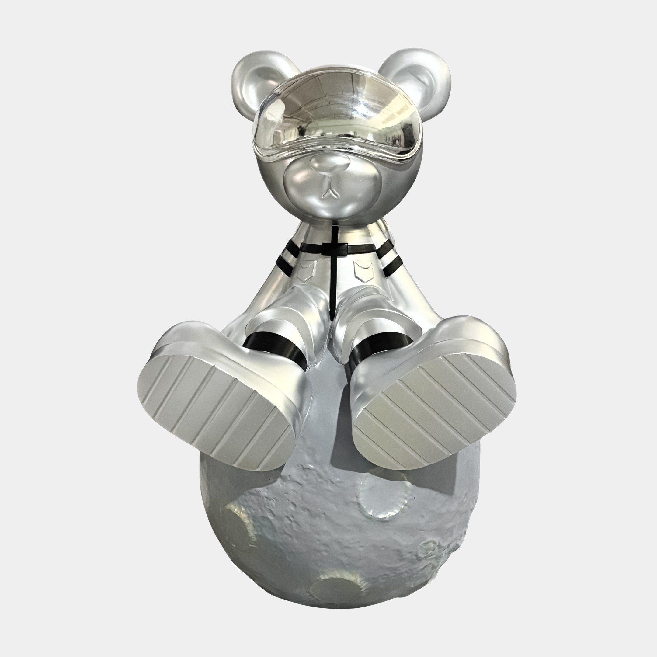 The Giant Sculptures Cosmic Chrome Astronaut Bear Moon Sculpture (80cm) features a shiny silver bear in a spacesuit with a reflective visor, seated on a textured gray moon, facing forward against a plain white background.