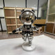 The Astral Silver Astronaut Bear Butler Sculpture (90cm) by Giant Sculptures stands on a round base holding a black tray. Its reflective visor adds futuristic charm, making it the perfect space-themed accent for your home.