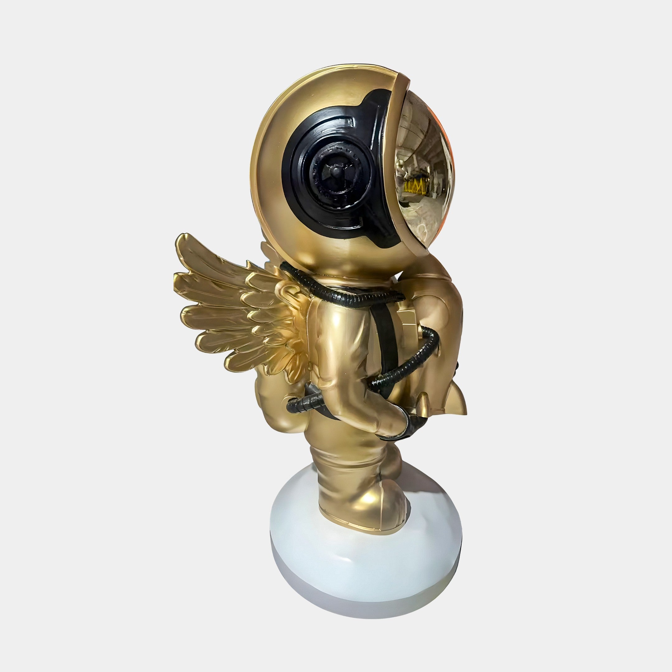 The Celestial Gold Astronaut Angel Rocket Sculpture (75cm) by Giant Sculptures features a gold astronaut with wings on a white base, black visor helmet, and hose, blending space and angelic themes for unique home decor.
