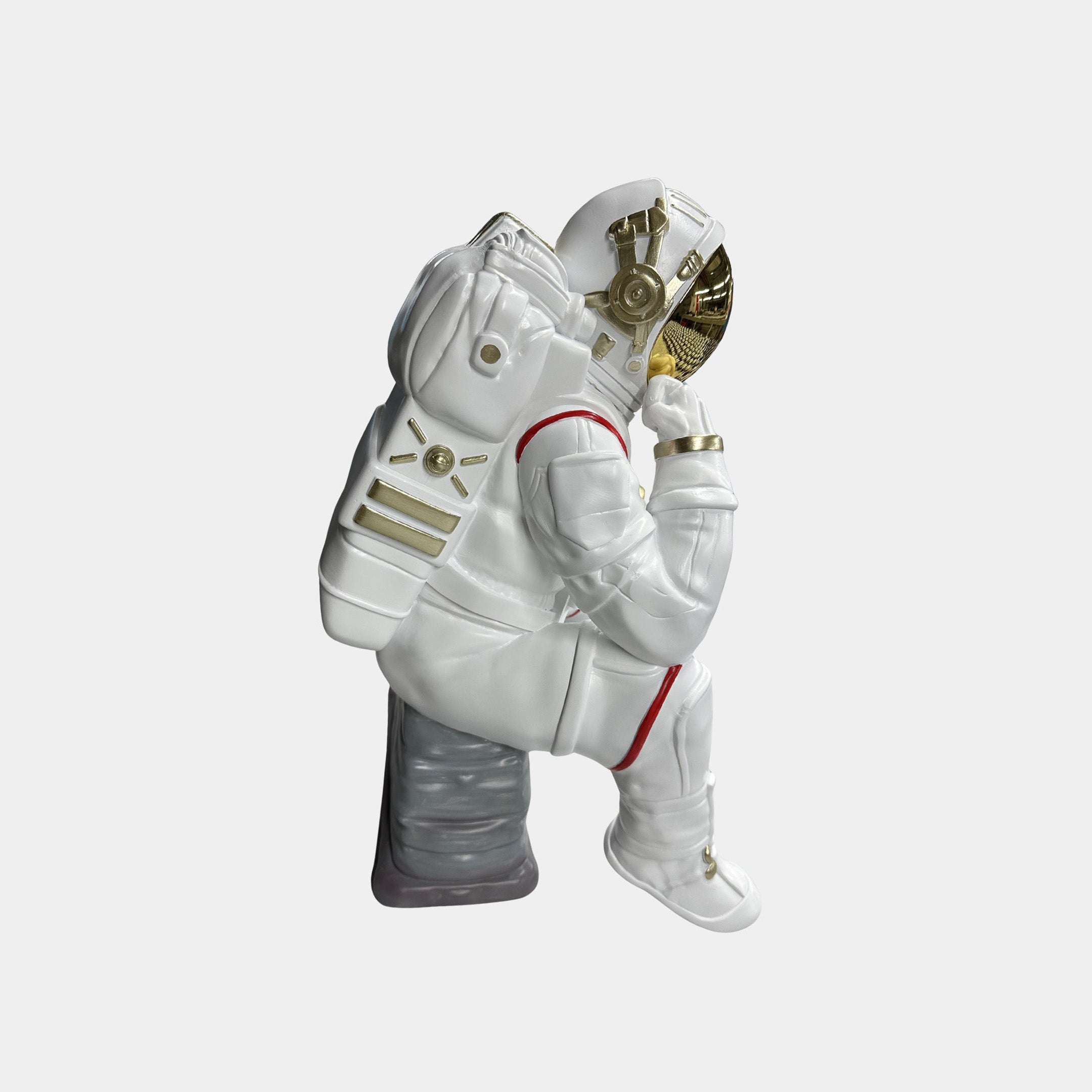 The Giant Sculptures Nova White Astronaut Thinker Figure (43cm) features a resin astronaut in a white suit with gold accents, posed thoughtfully on a gray rock—perfect for cosmic-themed home decor.