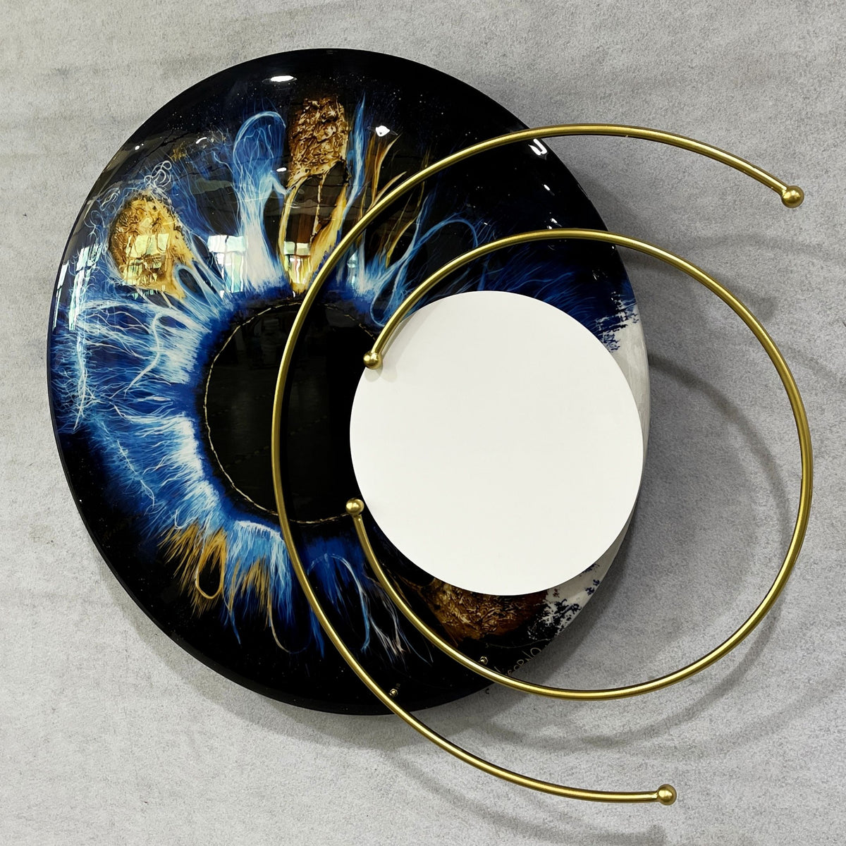 Aurelios Cosmic Blue Crystal Porcelain & Gold Orbit 3D Wall Art with a circular blue, black, and gold iris design, mirrored core, and gold orbiting rings, shown against a grey background.