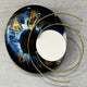Aurelios Cosmic Blue Crystal Porcelain & Gold Orbit 3D Wall Art with a circular blue, black, and gold iris design, mirrored core, and gold orbiting rings, shown against a grey background.