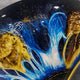 Close-up of the Aurelios Cosmic Blue Crystal Porcelain & Gold Orbit 3D Wall Art, showing deep blue crackling patterns and gold textured accents on a starry dark background.