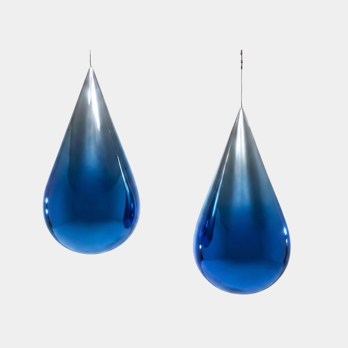 Bramleigh Blue Glass Droplets Sculpture - 60cm, pair of hanging teardrop-shaped fibreglass forms with mirror-bright blue finish, shown against a plain light background.