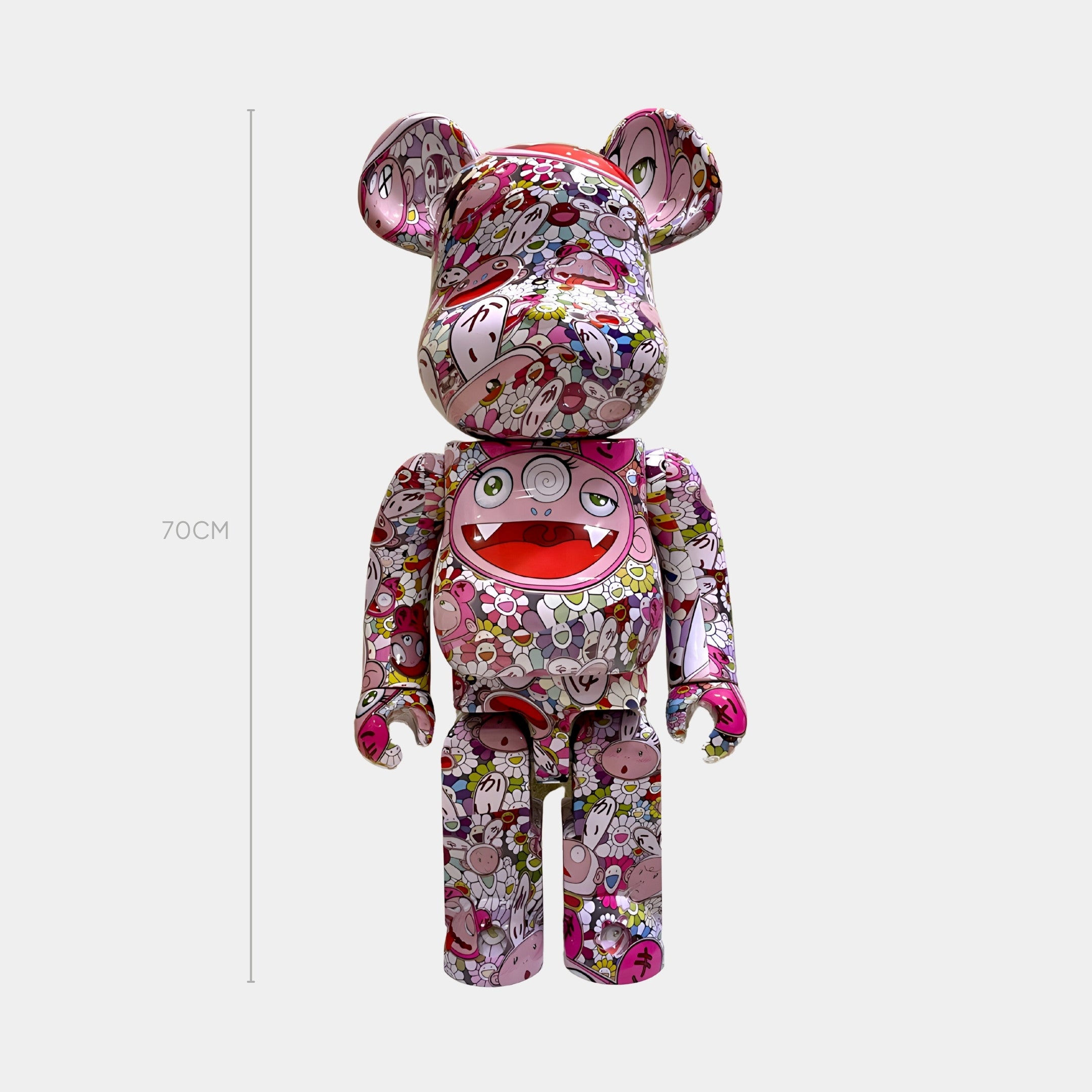 The Bloom Pop Bear Sculpture - 70cm by Giant Sculptures features colorful cartoon faces, flowers, and playful designs on a white base, inspired by Japanese Superflat pop art, with a large smiling mouth on its torso.