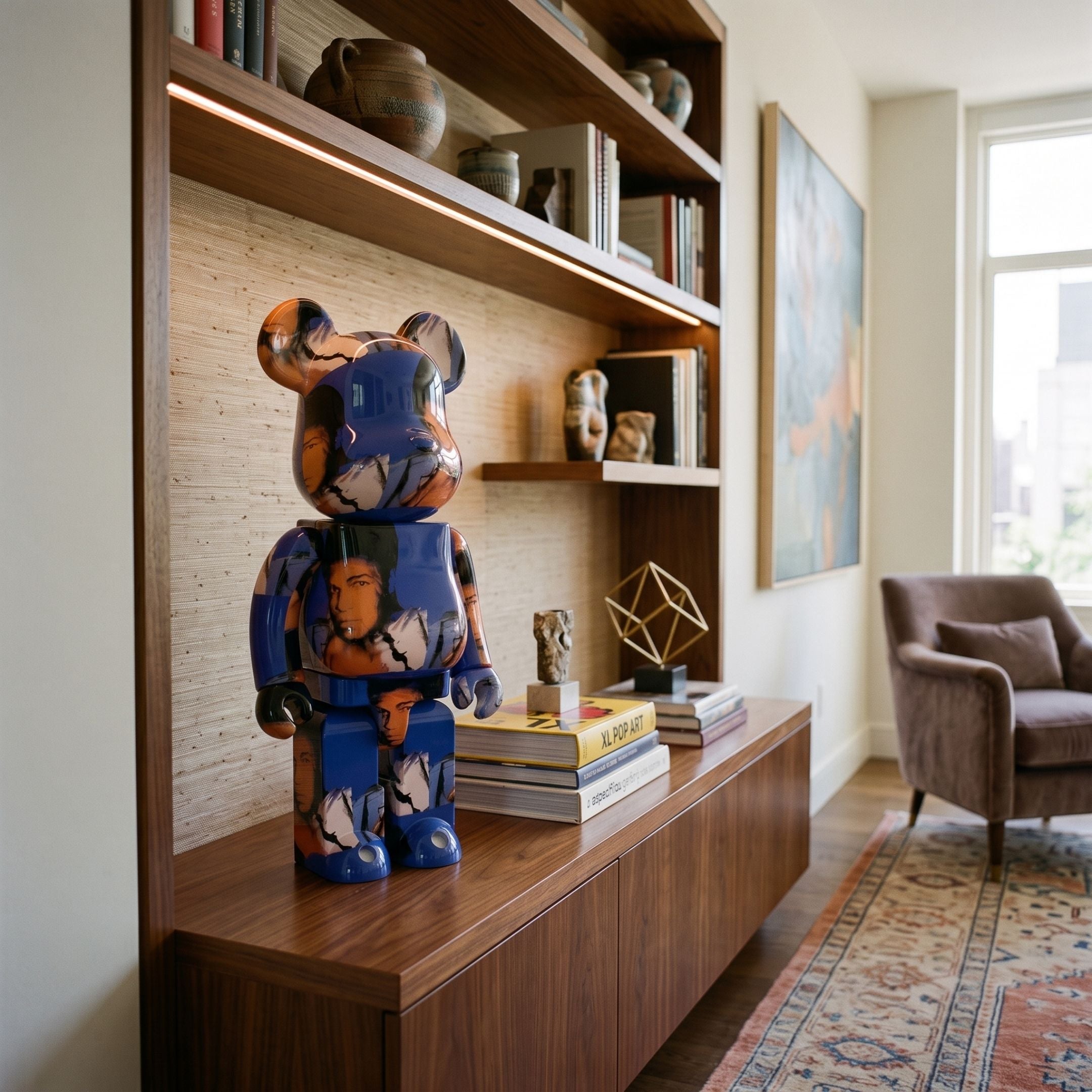 Blue Mosaic Muse Bear Sculpture - 70cm, glossy pop-art bear in blue, orange, and black tones on a wooden cabinet beside shelving and books.