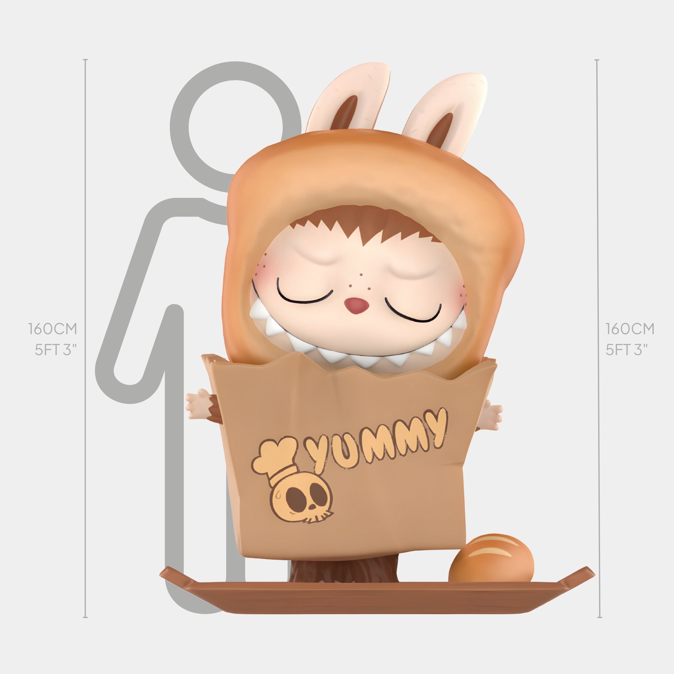 The Hidden Bread Bag Labubu Sculpture - 160cm by Giant Sculptures features a child in a brown bunny costume inside a YUMMY bakery-themed paper bag with a skull and chef hat, smiling sweetly with closed eyes.