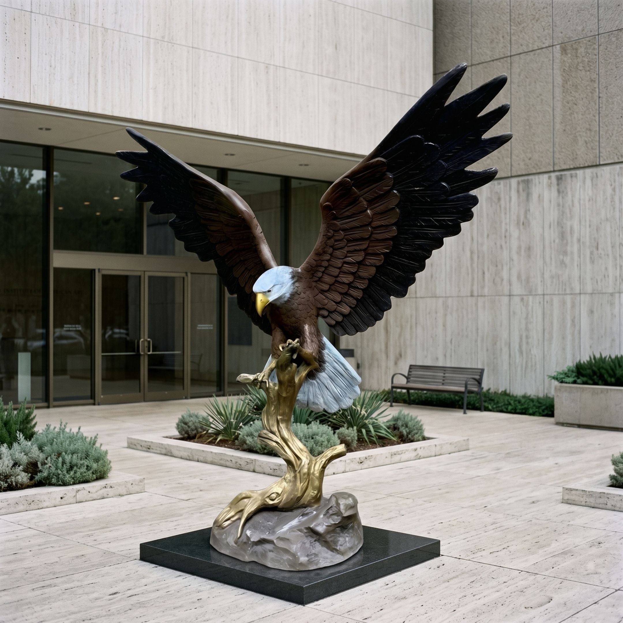 Monumental Traditional Bald Eagle Bronze Sculpture, 260cm, wings outstretched atop a gilded branch on a stone base, outside a building entrance.