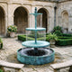 Monumental Contemporary Three-Tier Cascading Bronze Fountain, 280cm, in a stone courtyard with arched arcade, showing water sheeting from each tier into a ribbed basin.