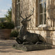 Life-Size Classical Recumbent Stag Bronze Sculpture by Giant Sculptures, dark patina finish, resting on a terrace beside a limestone château facade.
