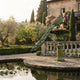 Monumental Classical Peacock Fountain Bronze Sculpture by Giant Sculptures with verdigris patina, tail cascading over a tiered basin beside a villa's lily pond.