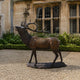 Life-Size Traditional Bugling Bull Elk Bronze Sculpture by Giant Sculptures shown mid-bugle with raised head and wide antlers on gravel outside a stone manor.