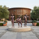 Life-Size Contemporary Musician Trio Bronze Sculpture by Giant Sculptures on a round stone base, featuring a flutist, seated guitarist, and violinist outside a curved wooden pavilion.