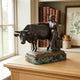 Traditional Milkmaid and Bull Bronze Sculpture by Giant Sculptures on a green marble base, displayed on an oak cabinet beside a window and leather books.