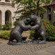 Monumental Fighting Bears Bronze Sculpture by Giant Sculptures, 350cm, two bears rearing on hind legs in confrontation with dark patina, outside a stone building.