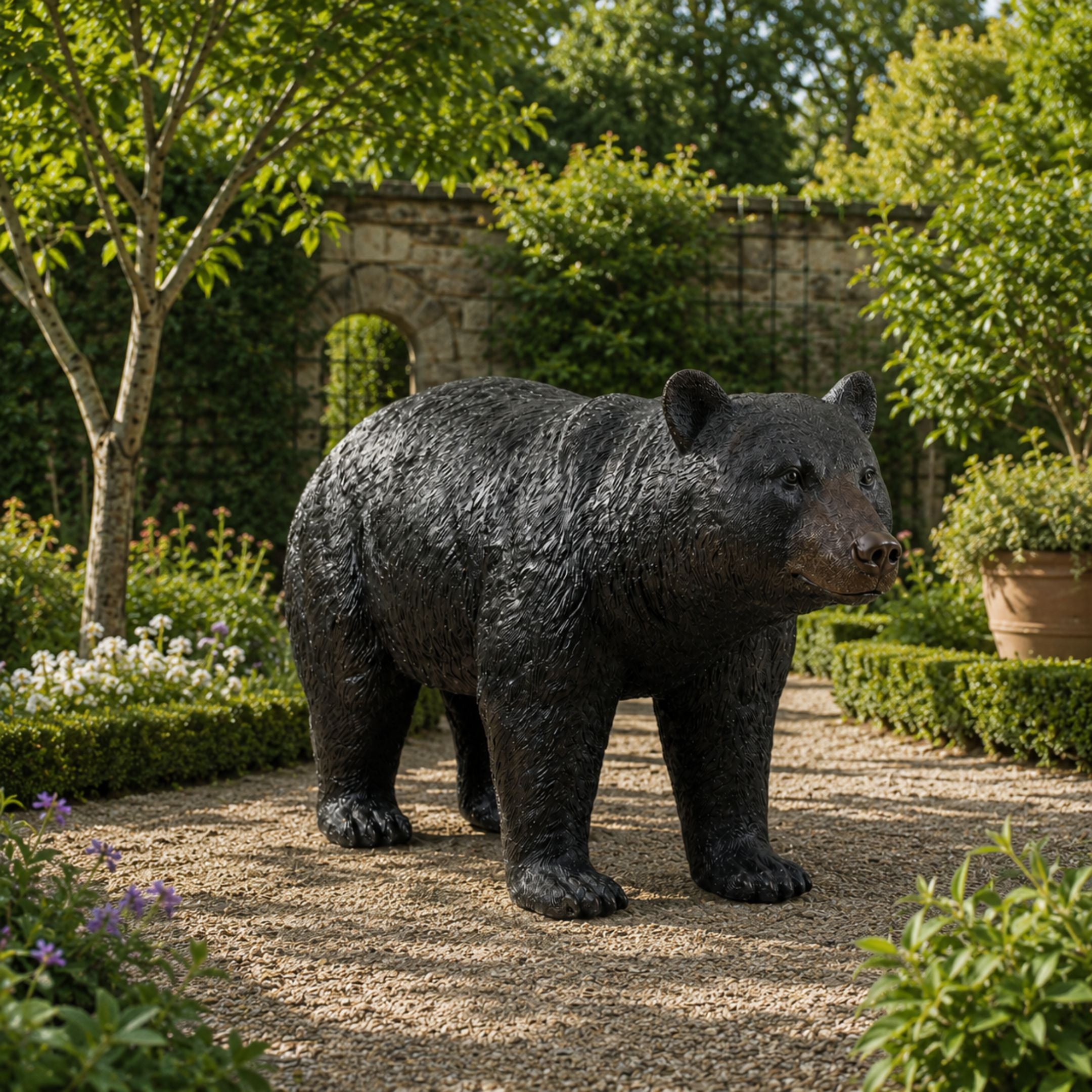 Life-Size Traditional Walking Bear Bronze Sculpture by Giant Sculptures with dark patina, mid-stride on a gravel garden path bordered by hedges and flowers.