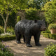 Life-Size Traditional Walking Bear Bronze Sculpture by Giant Sculptures with dark patina, mid-stride on a gravel garden path bordered by hedges and flowers.