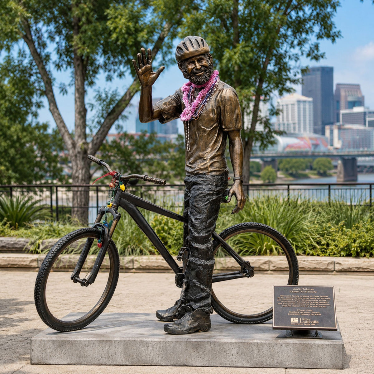 Life-Size Contemporary Bearded Cyclist and Bicycle Bronze Sculpture, 220cm, waving figure beside bicycle on stone base, outdoor park setting with city skyline.
