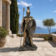 Life-Size Classical Spartan Warrior Bronze Sculpture, 190cm, standing with raised spear and round shield on a rocky base, patio setting overlooking the sea.