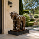 Large Contemporary Rotund Bull Bronze Sculpture, 220cm, dark bronze finish on a black marble base, displayed by an entrance beside a stone wall and garden.