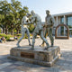 Monumental Contemporary Boxing Trio Bronze Sculpture, 250cm, by Giant Sculptures, showing two sparring boxers and a tracksuited trainer on a stone base in an outdoor plaza setting.