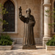 Life-Size Classical Robed Saint Bronze Statue, 300cm, hooded figure with raised blessing hand and book, set on a stone base outside arched windows.