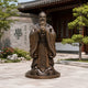 Life-Size Traditional Confucius Bronze Statue, 180cm, standing figure in flowing robes with hands clasped at chest, on a round base outside a traditional courtyard building.