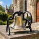 Traditional Church Bell Bronze Sculpture, 90cm, gold-toned bell in black iron yoke with wheel, displayed on stone base outside a church entrance.