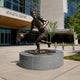 Life-Size Contemporary Basketball Player Bronze Sculpture, 250cm, dribbling in mid-stride on a round granite base outside an Athletic Center entrance.
